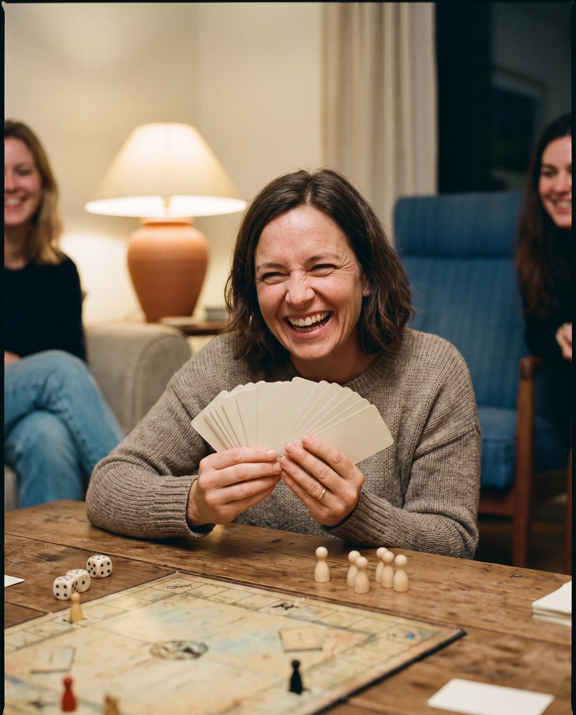 A person laughing while holding blank cards at a game table